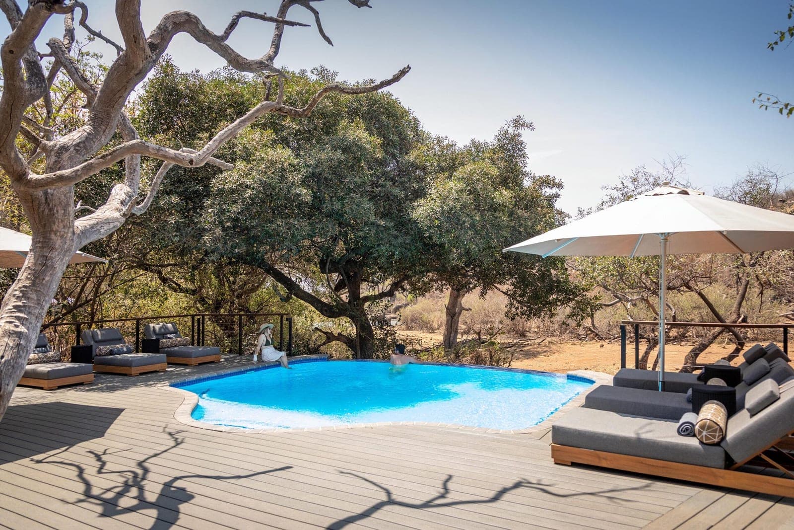 The pool deck and loungers under the trees at Tuningi Safari Lodge.